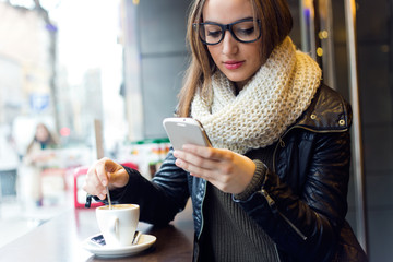 Beautiful girl using her mobile phone in cafe.