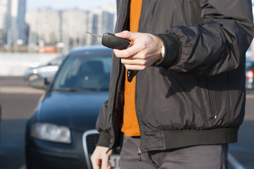 Male holding car keys with car on background