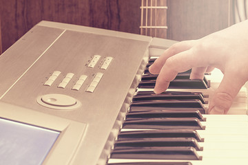 Male hand on the keyboard and guitar.