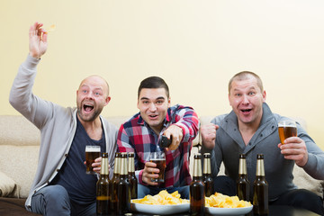 Three male friends sitting at table with beer