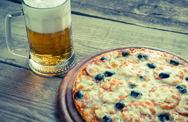 Cooked pizza with a glass of beer