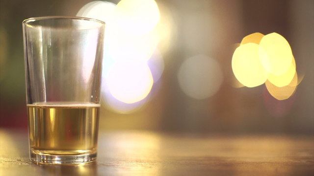 Nearly finished glass of beer with blurred background lights