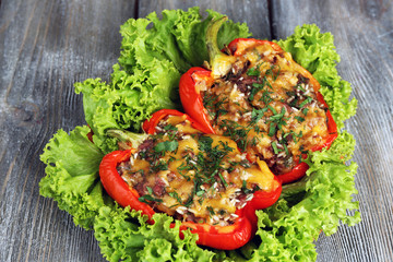 Stuffed red peppers with greens on plate on wooden table