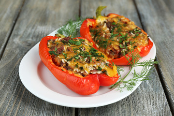 Stuffed red peppers with greens on plate on wooden table