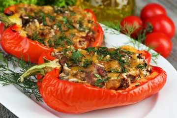 Stuffed red peppers with greens and vegetables on table close