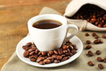Cup of coffee with beans on rustic wooden background