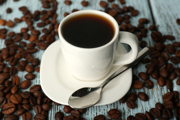 Cup of coffee with beans on color rustic wooden background