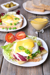 Fototapeta na wymiar Toast with egg Benedict and tomato on plate on wooden table