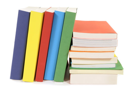 Small row line of colorful books spine facing with stack pile alongside isolated white background photo
