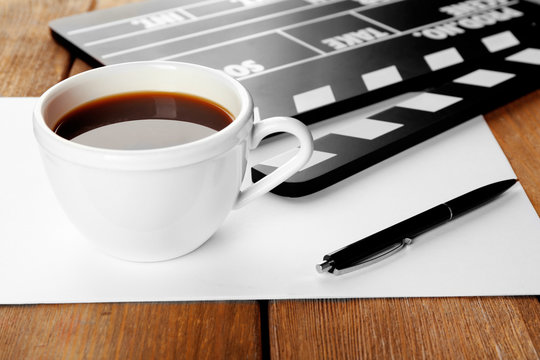 Movie clapper with paper, pen and cup of coffee
