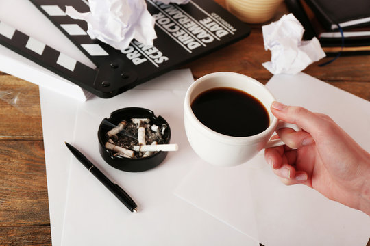 Female hand with cup of coffee, moving clapper and sheets of