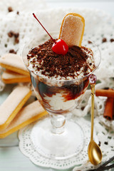 Tasty tiramisu dessert in glass, on wooden background