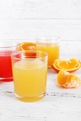 Different sliced citrus fruits and glasses of juice