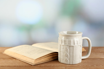 Cup of tea and book on table, on bright background