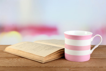 Cup of tea and book on table, on bright background