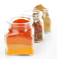 Different kinds of spices in glass bottles isolated on white