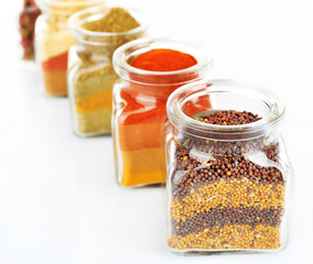 Different kinds of spices in glass bottles isolated on white