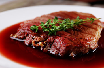 Grilled steak in wine sauce on plate close up