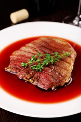 Grilled steak in wine sauce on plate on table close up