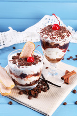 Tasty tiramisu dessert in glasses, on color wooden background