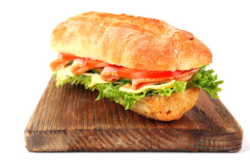 Fresh sandwich on wooden cutting board isolated on white