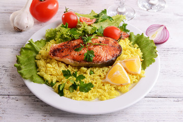 Tasty baked fish with rice on plate on table close-up