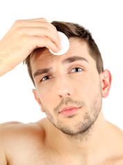 Obraz premium Handsome young man cleansing face isolated on white