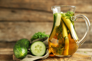 Glass ewer with fresh organic cucumber water on wooden table