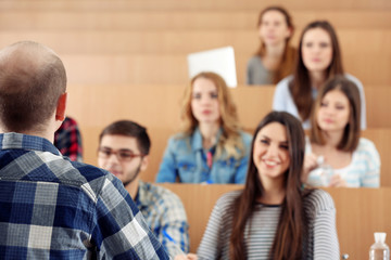 Group of students sitting in classroom and  listening teacher