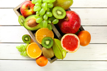 Assortment of fruits in box on wooden table
