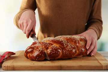 Cutting bun on wooden board on bright background
