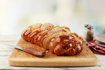 Sliced fresh bun on cutting board on bright background