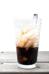 Half empty Vietnamese ice coffee glass on a wooden table against