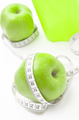 Green apple with measuring tape and glass