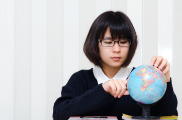 Teenage schoolgirl pointing a place on a globe with her finger