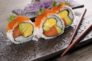 California roll sushi with chopsticks on a black plate