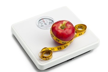 apple tied with tape measure on weight scale