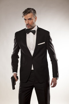 handsome man in a suit with a gun in his hand