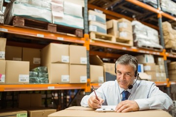 Fototapeta premium Manager looking at camera while writing on clipboard