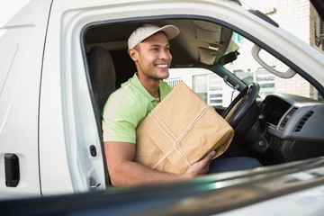 Smiling delivery driver in his van holding parcel