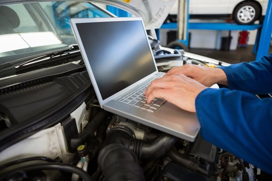 Mechanic using laptop on car