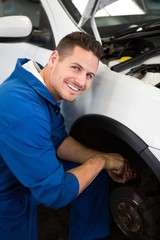 Smiling mechanic adjusting the wheel