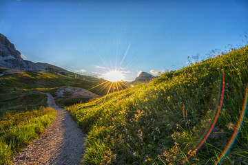 Sunstar at sunset on a trail in the meadows, Dolomites, Italy - obrazy, fototapety, plakaty