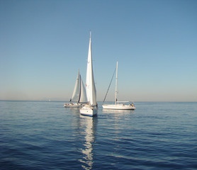 three yachts on a calm sea surface