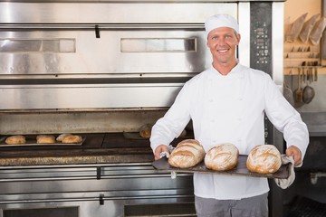 Happy baker holding tray of fresh bread
