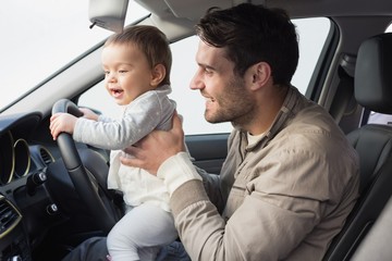 Father playing with baby in drivers seat