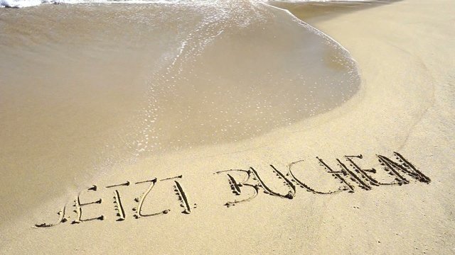 Text jetzt buchen in Sand gezeichnet wird von Wellen weggesp&uuml;lt