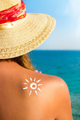  Beautiful girl with  sun tan cream on her back over sea backgro
