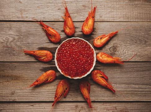 Boiled shrimps around bowl with red caviar