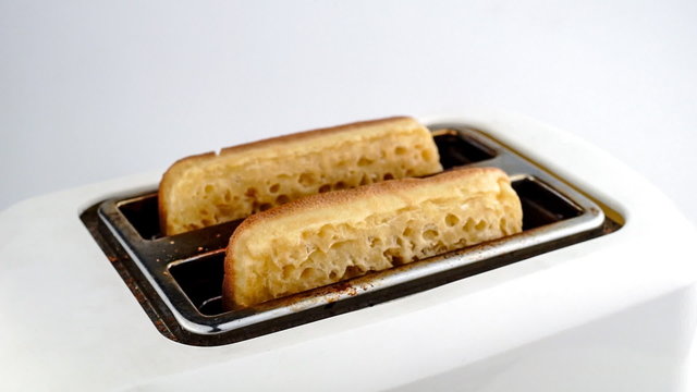 Crumpets being toasted and popping out of toaster isolated